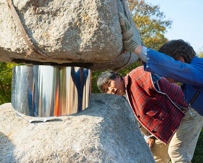 Das Foto zeigt des Künstler beim sorgsamen Errichten der Skulptur mitten in der Stadt Angermünde.